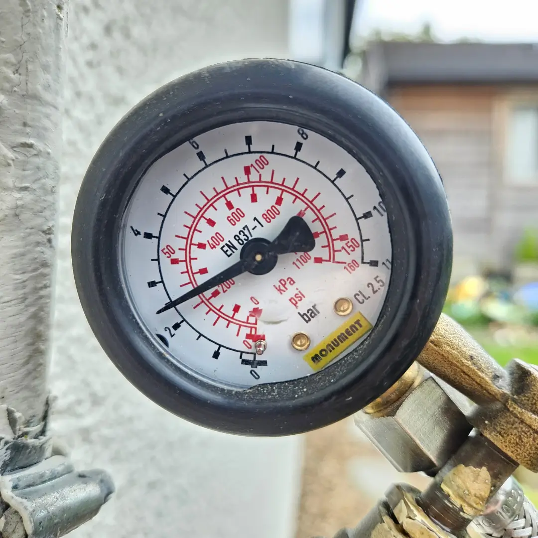 Close-up of a pressure gauge on pipework, used to detect hidden water leaks. (84 characters